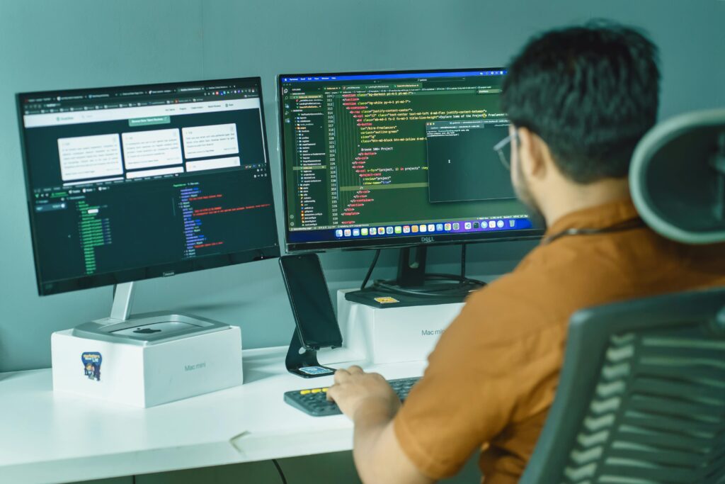 pexels photo 16323581 16323581 A software developer engaged in coding on dual monitors in a modern office setting.